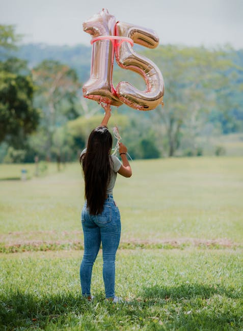 Woman holding 15 balloons in a field